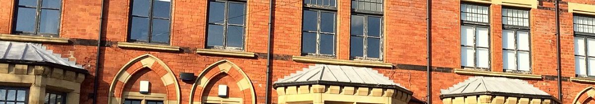 Upper storeys of a Victorian brick and stone building with tall sash windows